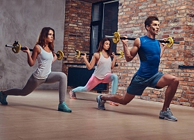 两个健身妇女和一个教练, 伸展蹲与杠铃在俱乐部内部阁