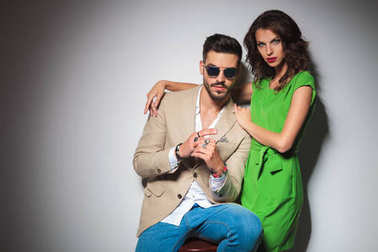 穿着绿色礼服的性感女人拥抱她坐着的男人