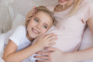 微笑的女儿听怀孕的母亲