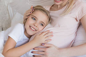 微笑的女儿听怀孕的母亲