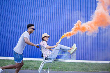 年輕的人夫婦騎在手推車上的空店在日出和有好好玩的時間