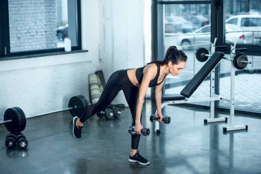 年轻运动的妇女工作与杠铃在健身房