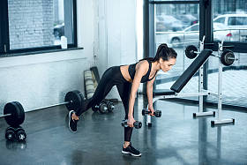 年轻运动的妇女工作与杠铃在健身房