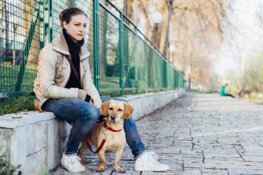 婦女坐和休息的圍欄與她的狗