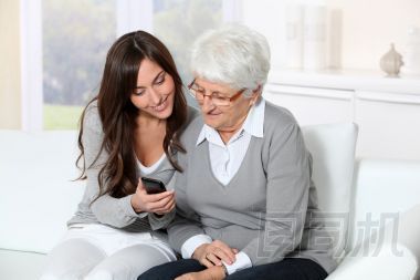 顯示如何使用移動電話的祖母的年輕女子