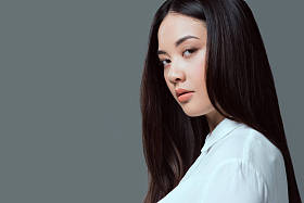 美丽的亚洲女孩近距离肖像看着相机孤立在灰色