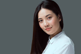 美丽的年轻亚洲女人的肖像在镜头上微笑孤立的灰色 