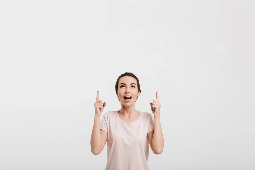 美丽的女孩指向的东西和寻找孤立的白色