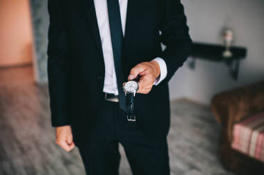 早在婚禮前新郎或時尚男子商人把手表放在他的手