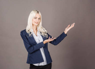 微笑的女人在灰色背景上展示了一些东西。生活方式