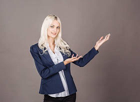 微笑的女人在灰色背景上展示了一些东西。生活方式