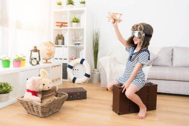 快樂漂亮的孩子飛行員坐在老式的手提箱