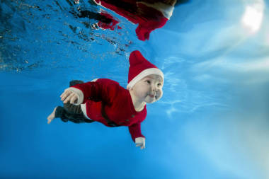 一個(gè)小男孩在圣誕老人的成本游泳水在水池