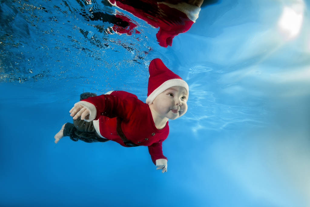 一个小男孩在圣诞老人的成本游泳水在水池 一个小男孩在圣诞老人的成本游泳水在水池