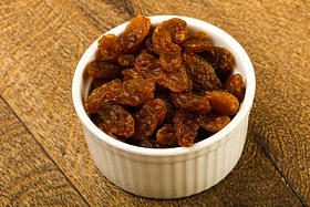 在木制的背景干葡萄干放在碗