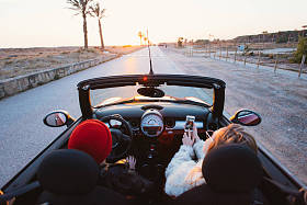 用智能手机与人的敞篷跑车的妇女画像 