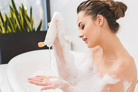 年轻女子沐浴用凝胶和泡沫的侧面图 