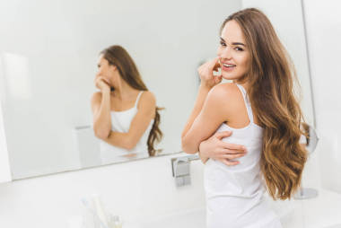 在家里的浴室里看着镜头的美丽的年轻女子的肖像