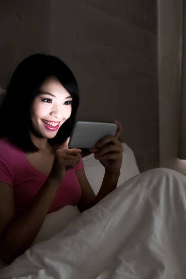 在晚上愉快地玩手机游戏的妇女