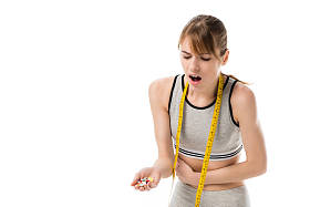 年轻的女人与胃痛举行堆药片隔离在白色