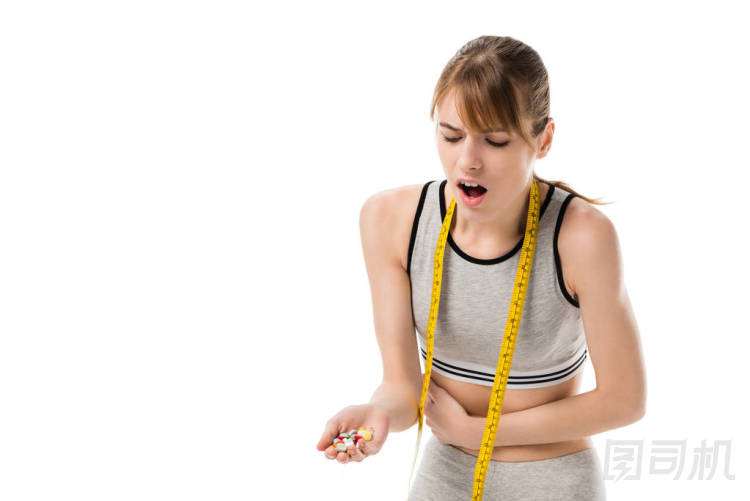 年輕的女人與胃痛舉行堆藥片隔離在白色