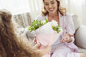 女儿在母亲节快乐的母亲面前献上花束给她微笑的妈妈