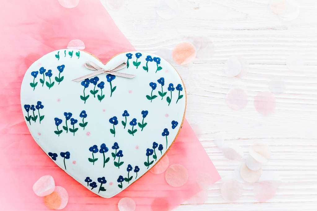 饼干心与蓝色的花朵在白色质朴的木制背景与五彩纸屑平躺。文本空间。母亲节快乐贺卡。情人节或妇女的快乐 饼干心与蓝色的花朵在白色质朴的木制背景与五彩纸屑平躺。文本空间。母亲节快乐贺卡。情人节或妇女的快乐