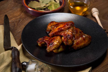 烤鸡翅配蜂蜜在食品背景黑盘子上供应