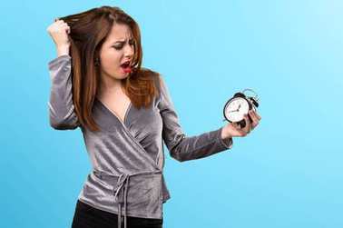 美丽的年轻女孩举行复古时钟在多彩的背景