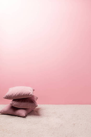 粉红色墙壁前地毯上的枕头照片