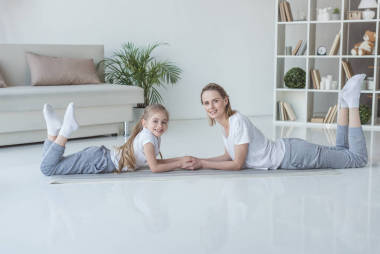 轻松的母亲和女儿躺在地板上一起看着相机