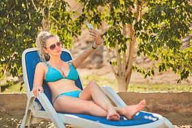 热带度假胜地的比基尼女子日光浴。美丽的女人躺在太阳躺椅