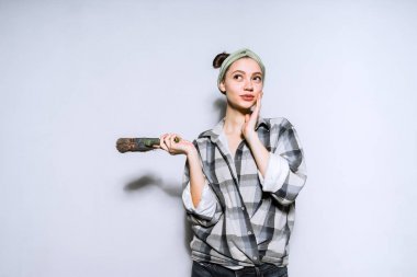 一个年轻的女孩想修理她的公寓, 拿着一把刷子