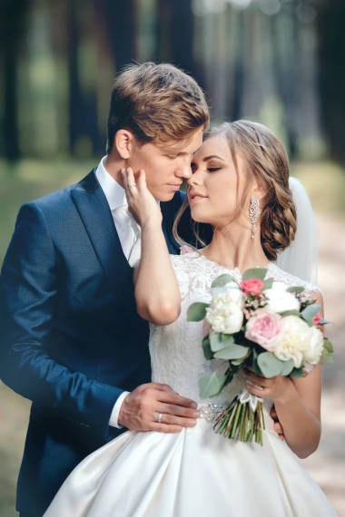 新娘和新郎在婚礼礼服上的自然背景。结婚日。新婚夫妇正在森林里漫步