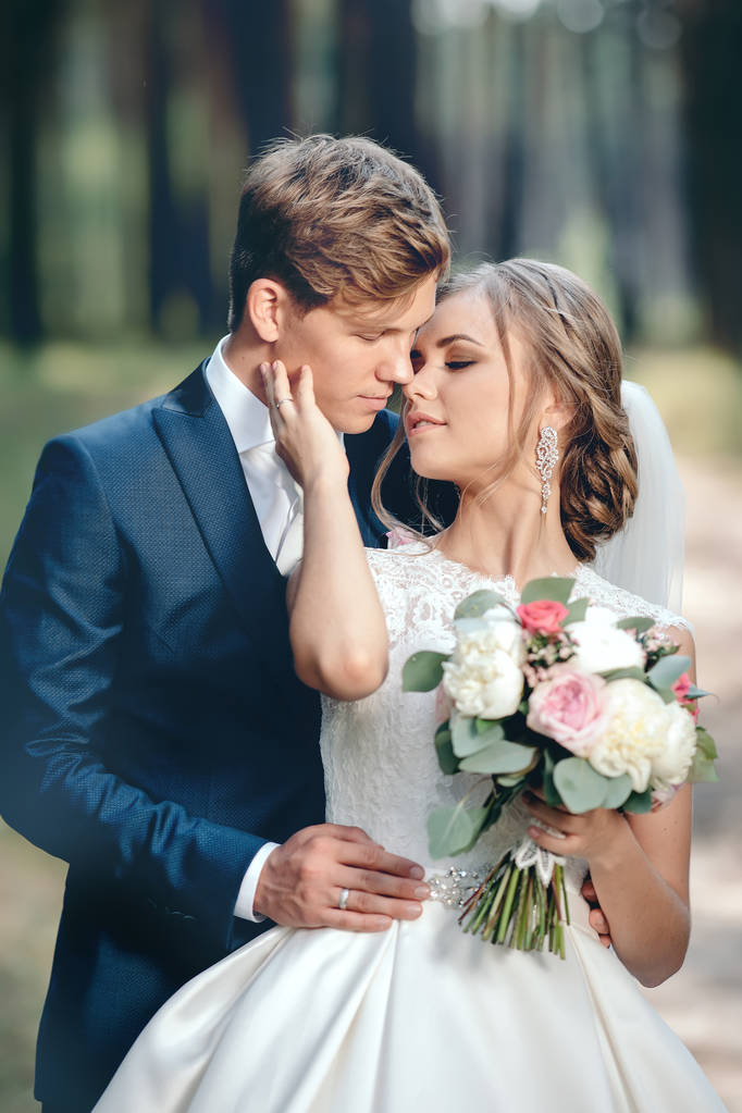 新娘和新郎在婚礼礼服上的自然背景。结婚日。新婚夫妇正在森林里漫步 新娘和新郎在婚礼礼服上的自然背景。结婚日。新婚夫妇正在森林里漫步