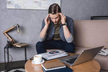 坐在沙发上头疼的年轻商人照片