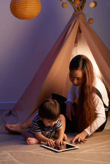 亚洲年轻女子与她的小儿子玩平板电脑