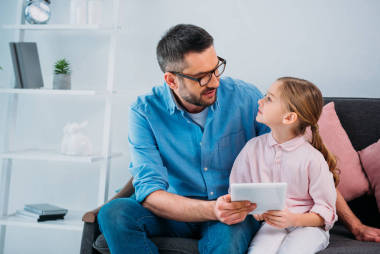 在家用平板電腦微笑的父親和女兒一起