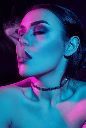 魅力诱人的华丽的黑发妇女吸烟电子香烟