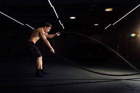 与战斗健身的人锻炼的绳索在健身房。训练演习在俱乐部安装了身体。躯干