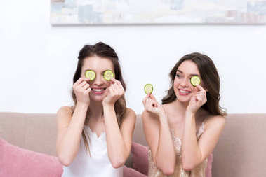 美麗的微笑的女孩在睡衣拿著黃瓜片近眼睛