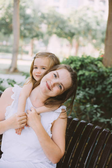 美麗的年輕女子與她的小女兒放松在長凳上夏季公園