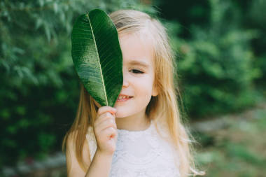  小女孩手持绿叶覆盖面, 特写 
