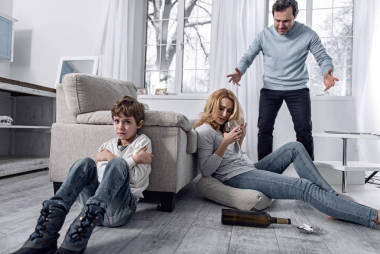 當(dāng)一個憤怒的父親和他的酗酒的妻子吵架時, 受驚的男孩哭了