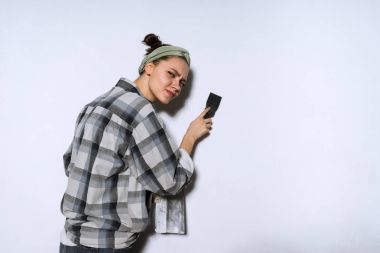 滑稽的年轻女孩在格子衬衫溅墙与铲, 修复
