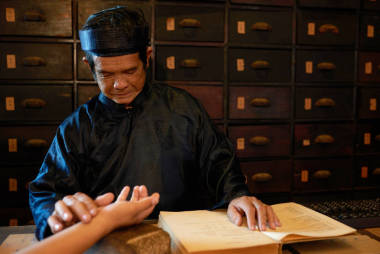 中醫(yī)醫(yī)師檢查脈搏的女性患者