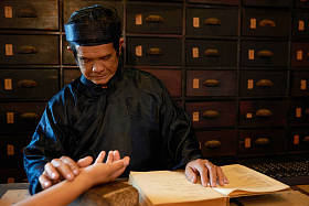 中医医师检查脉搏的女性患者