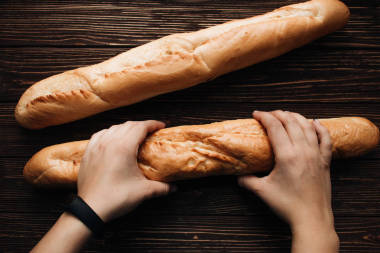 女性手打破美味新鮮脆法國游蕩在木桌上