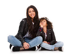 时尚的母亲和女儿的皮夹克坐在地板上孤立的白色