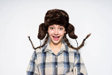 快樂(lè)年輕的俄羅斯女孩在一個(gè)溫暖的帽子與耳朵襟翼笑